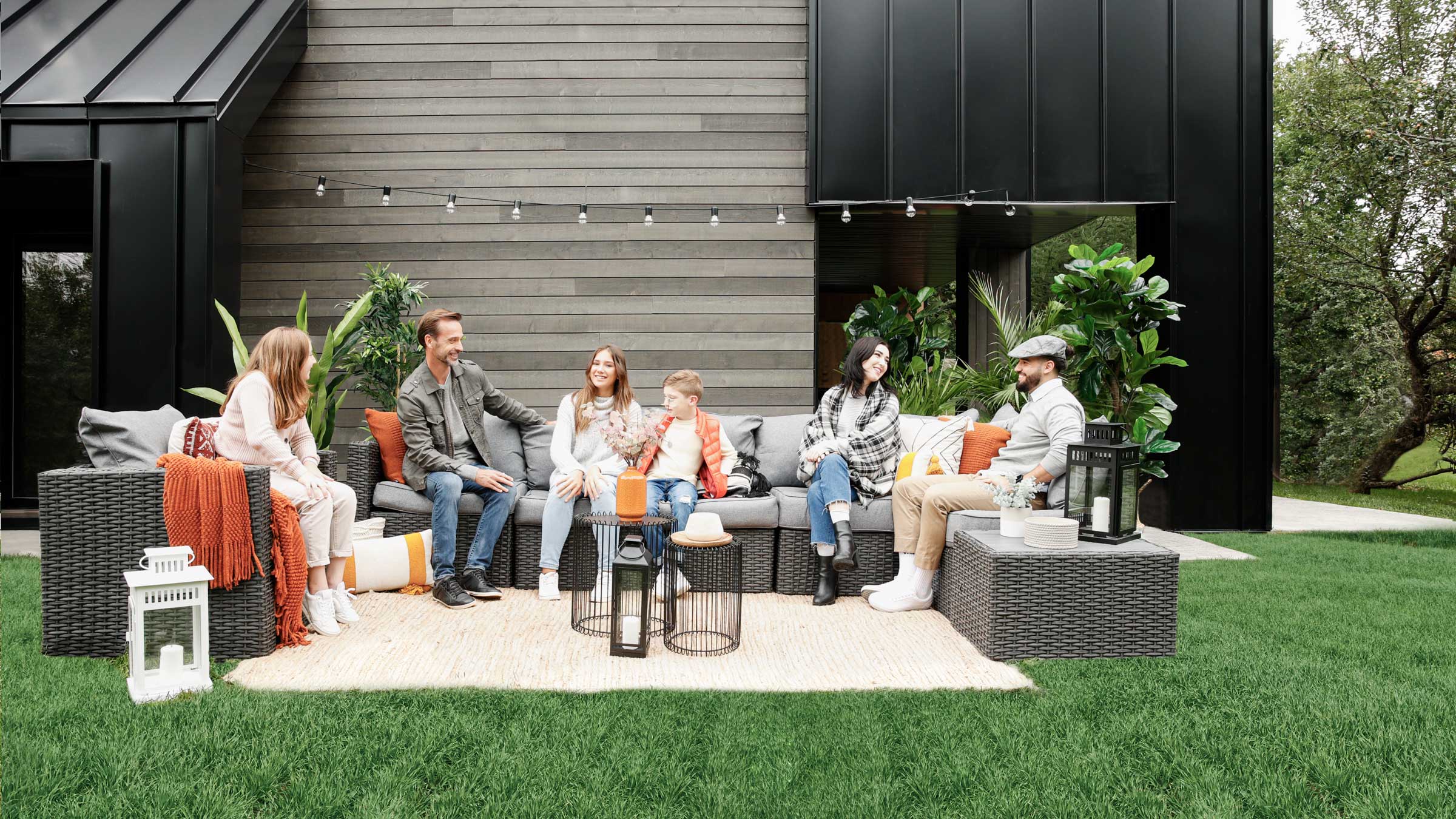 A family sitting outside on their backyard furniture.