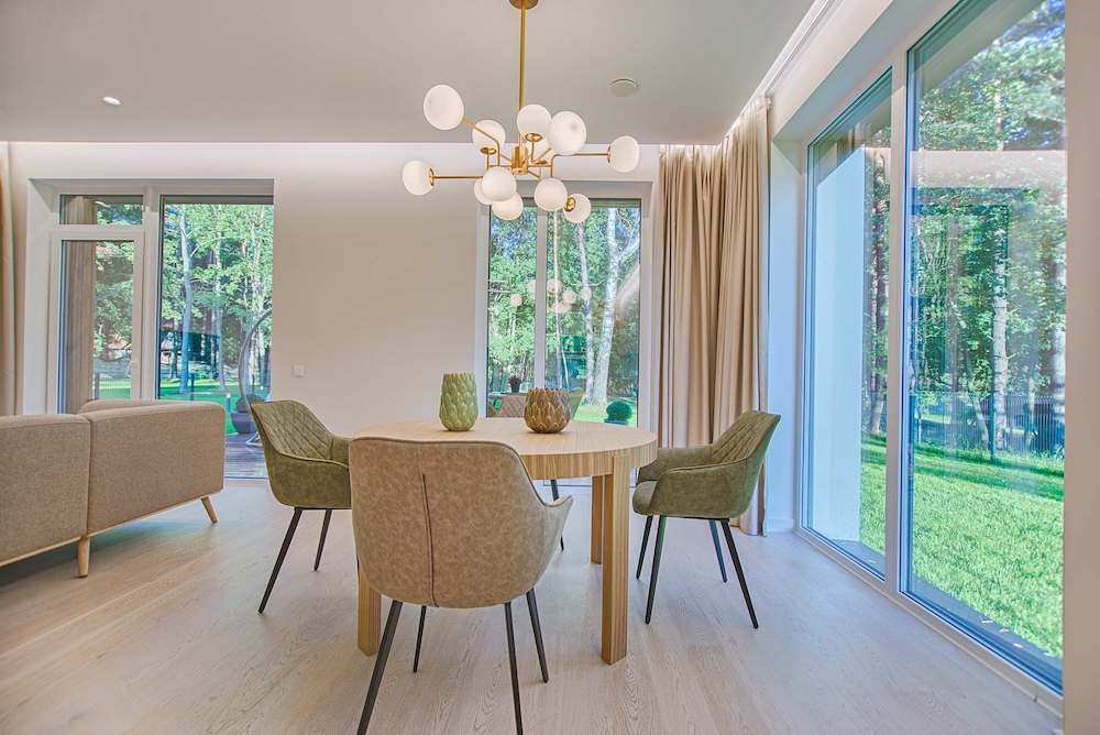 A modern living room and dining room with a chandelier over the table.