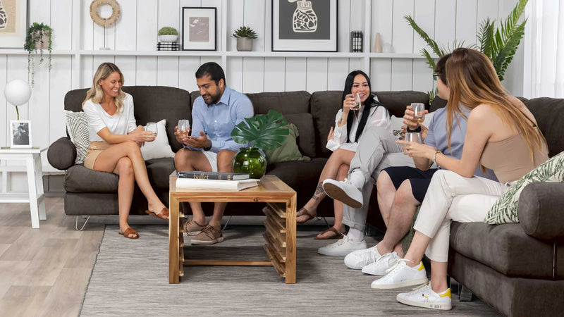 Friends sitting on a modern sectional couch while at a dinner party.